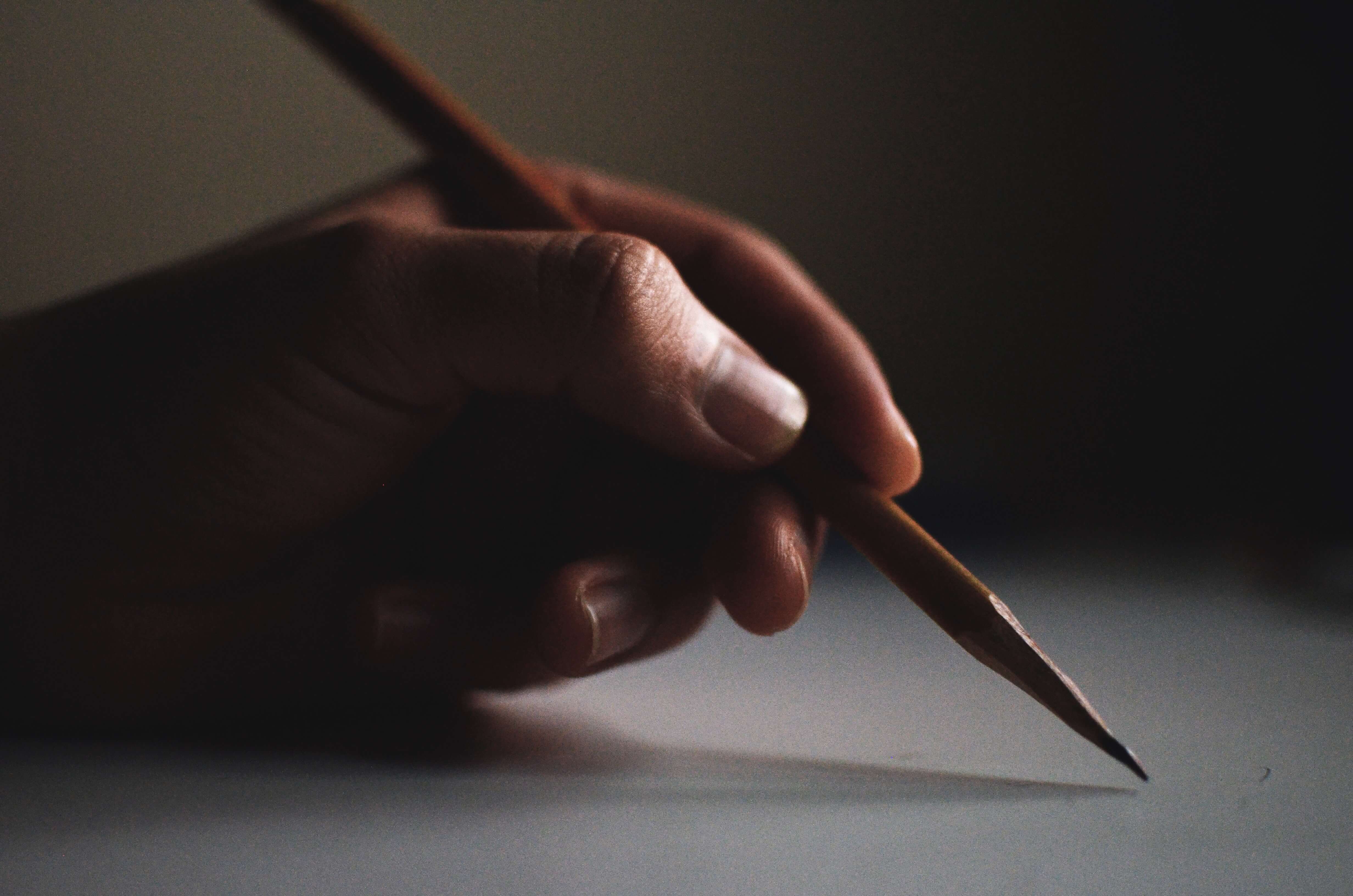 A close-up of a hand writing with a pencil