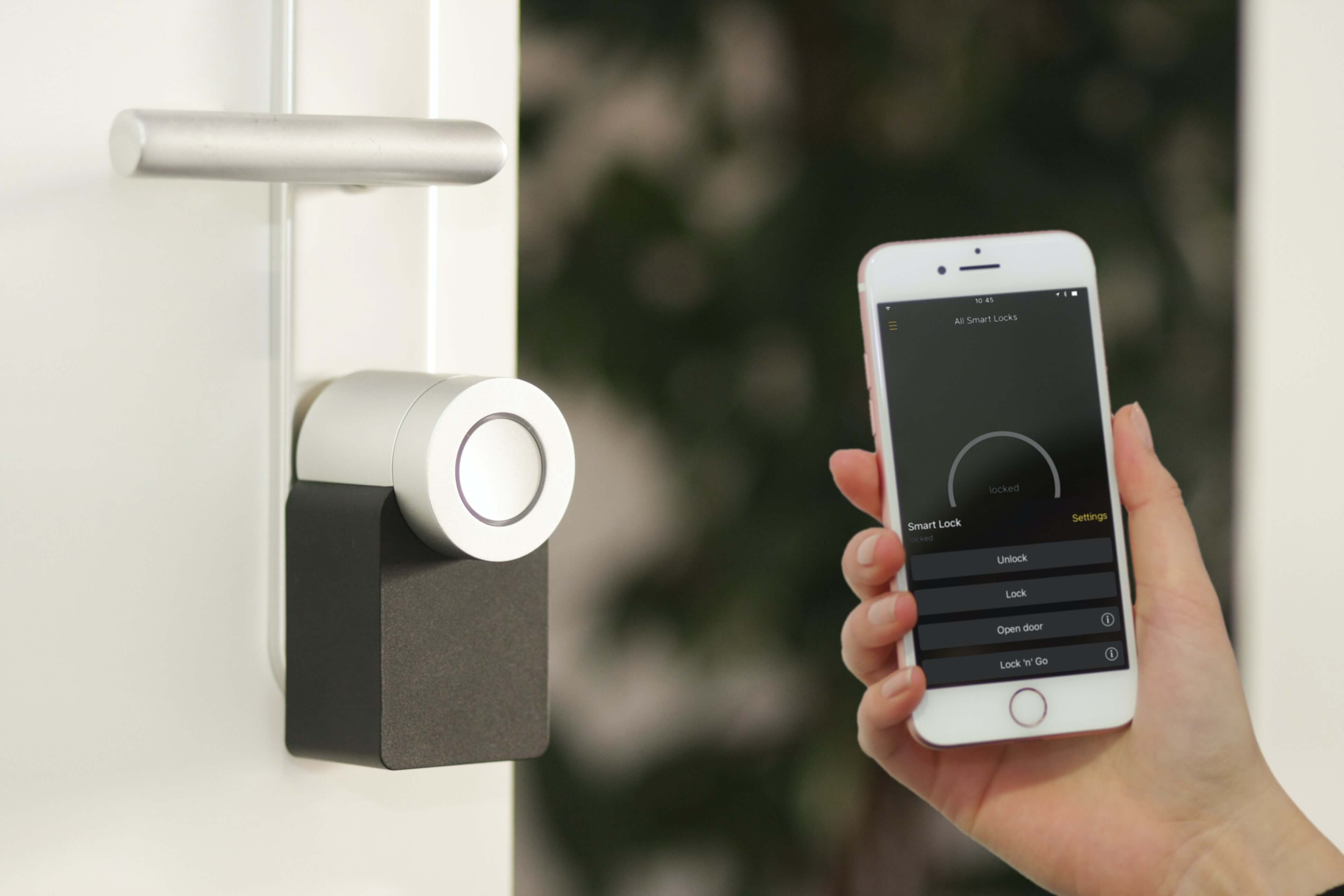 A person holds up a phone to a smart lock. 