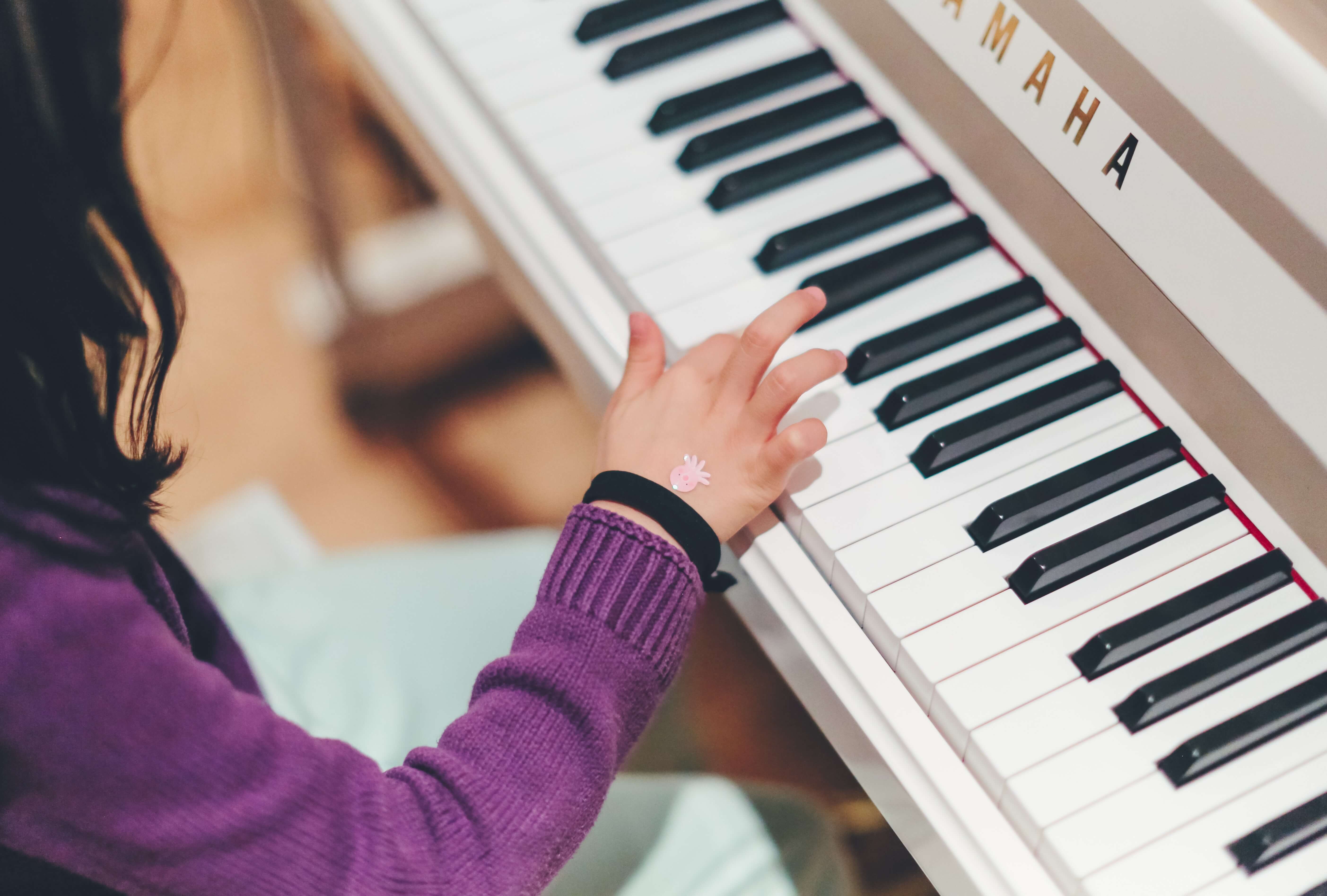 A little girl with dark hair plays an electric piano