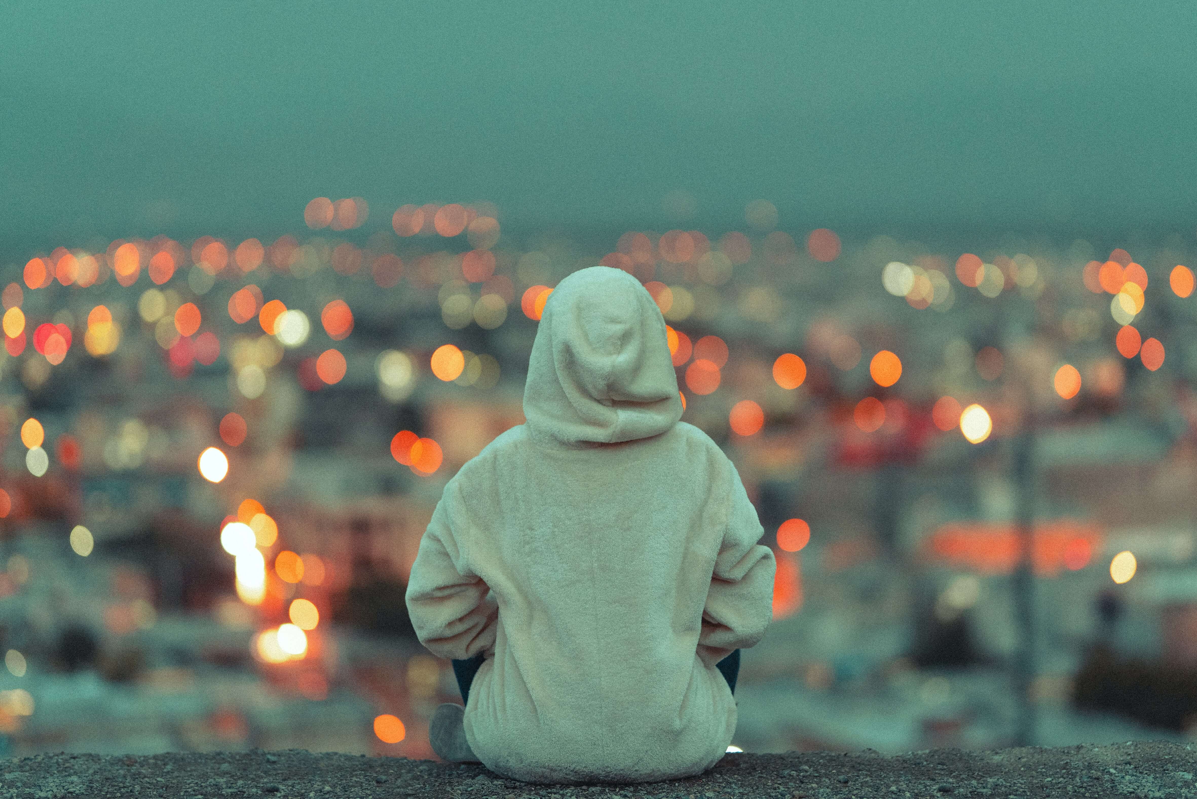 A person in a hoodie looks out at the horizon with their back to the camera
