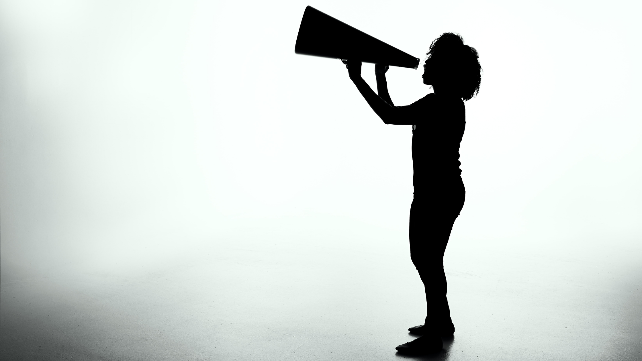 A silhouette of a person speaking into a megaphone.