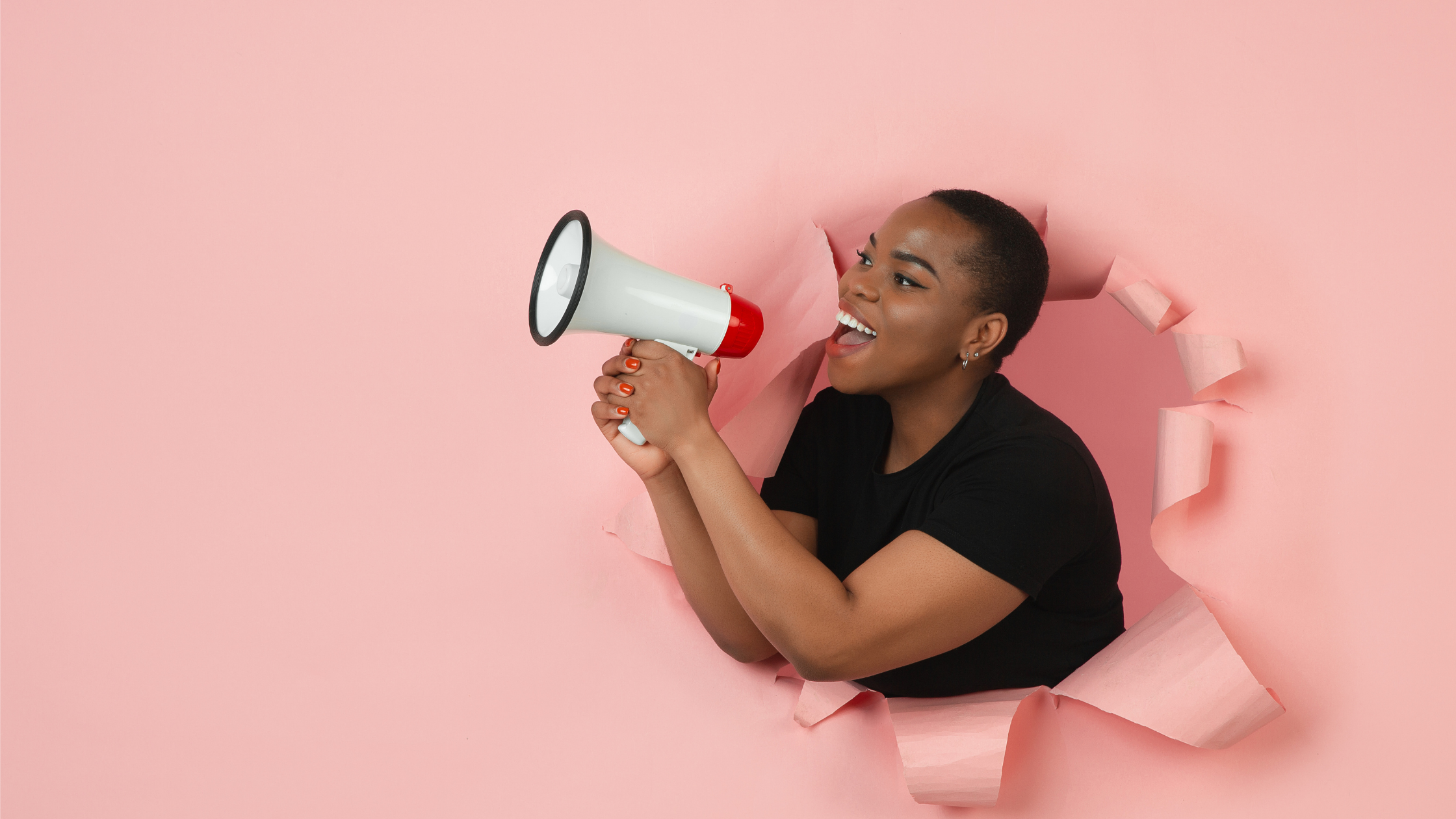 A black woman bursting through a pink background with a megaphone