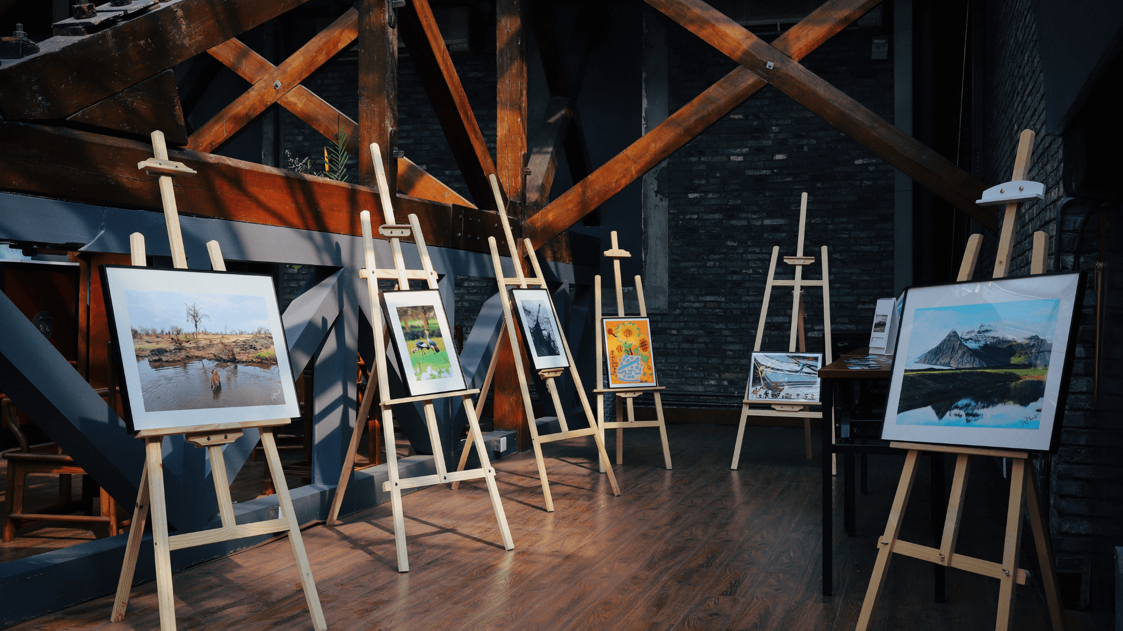 Easels with paintings set up around a rustic gallery room